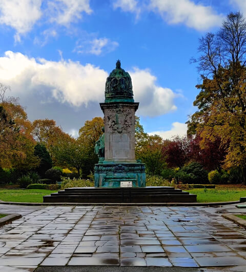 Statue at Woodhouse Moor/Hyde Park against a blue sky and wet ground