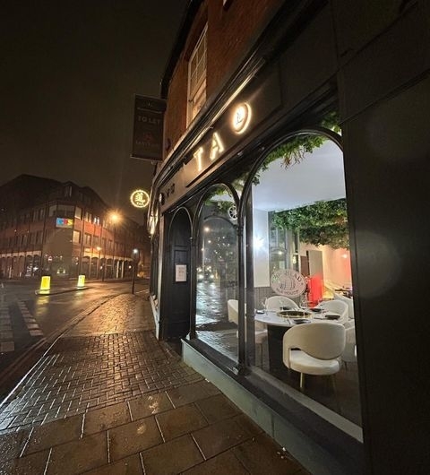 Exterior view of TAO at night, showcasing its illuminated signage and inviting storefront with visible dining area through the window.