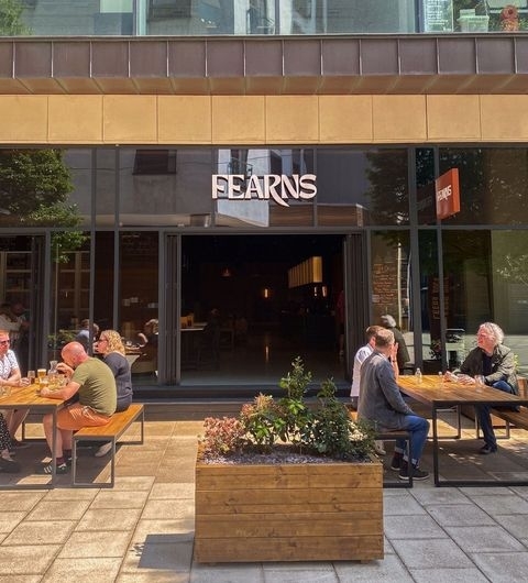 Visitors enjoying outdoor seating at Fearns Dock with a clear view of the establishment's entrance and signage.