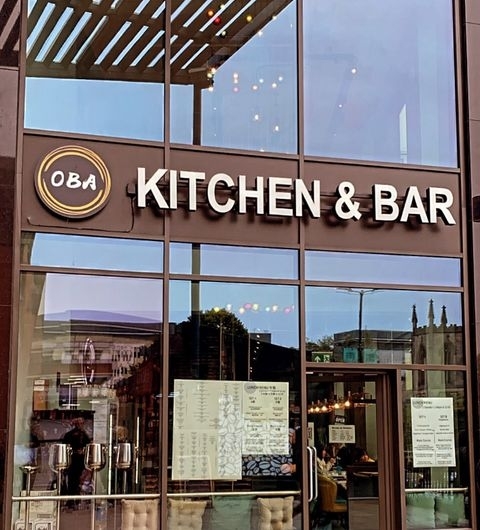 Exterior view of Oba Korean & Japanese Kitchen & Bar with signage above the entrance, reflecting the evening sky in large glass windows.