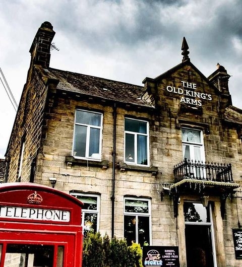 Alt text: "Exterior view of The Old King's Arms, featuring its stone facade and sign, with a traditional red telephone box in the foreground."
