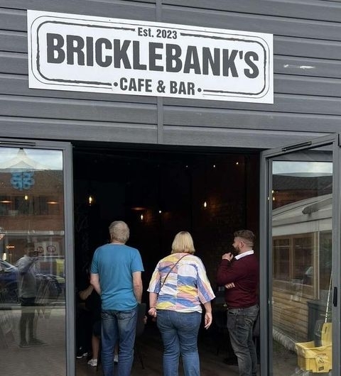 Patrons entering Bricklebank's Bar & Kitchen, showcasing the establishment's entrance and sign.