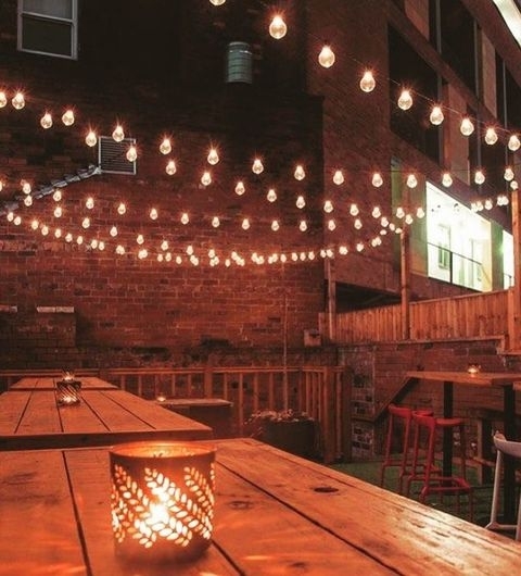 Cozy evening ambiance at Roland's with string lights over wooden tables and a lit candle centerpiece.