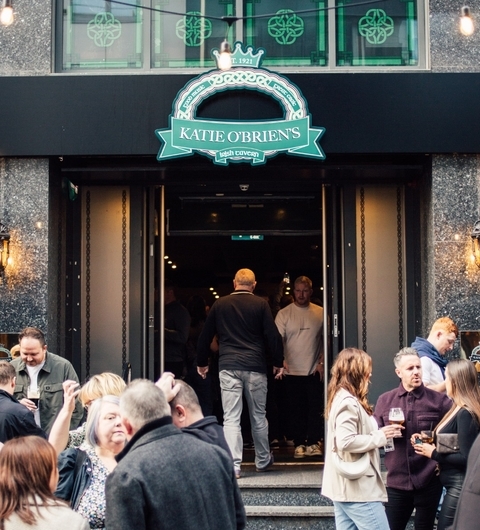 Crowd enjoying drinks outside Katie O'Brien's Irish Tavern, with a lively atmosphere and green signage above the entrance.