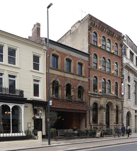 Historic brick buildings line the street, with outdoor seating and greenery, creating a welcoming dining atmosphere.