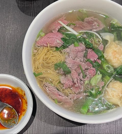 Pho noodle soup with beef, greens, and dumplings served with chilli sauce at Lento Cafe Leeds