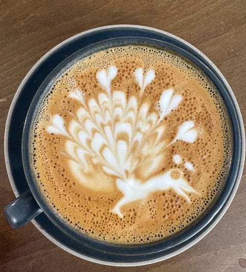 Intricate peacock latte art in a blue cup at The Barn Coffee Shop Meanwood Leeds