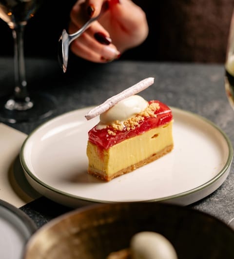 Raspberry and custard tart slice with cream quenelle beside a white wine glass at CrowdedHouse