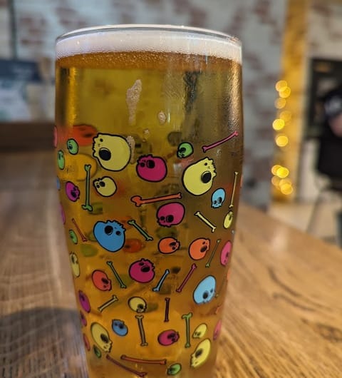 The Beer House Leeds — branded polka-dot skull pint glass with beer on wooden table