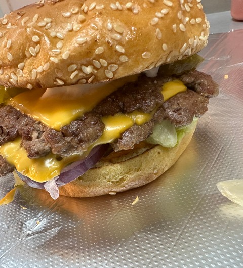 A double smash burger with melted cheddar, red onion and pickles in a sesame brioche bun, served at Smash Down Leeds.
