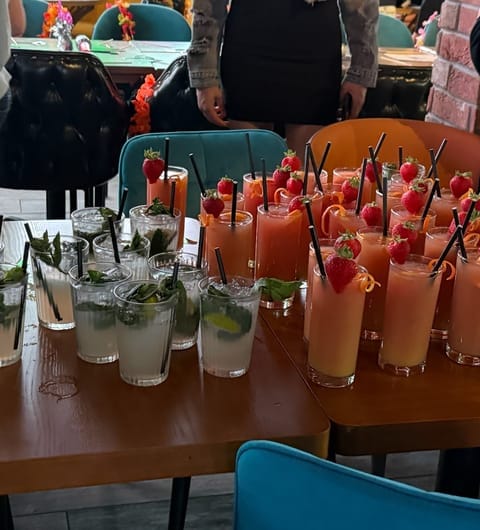 Row of cocktails at TAPAS BAR by olive branch including mojitos and pink strawberry garnished drinks ready to serve