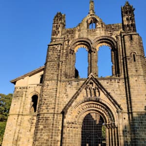 Looking up at Kirkstall Abbey against a blue sky in the afternoon