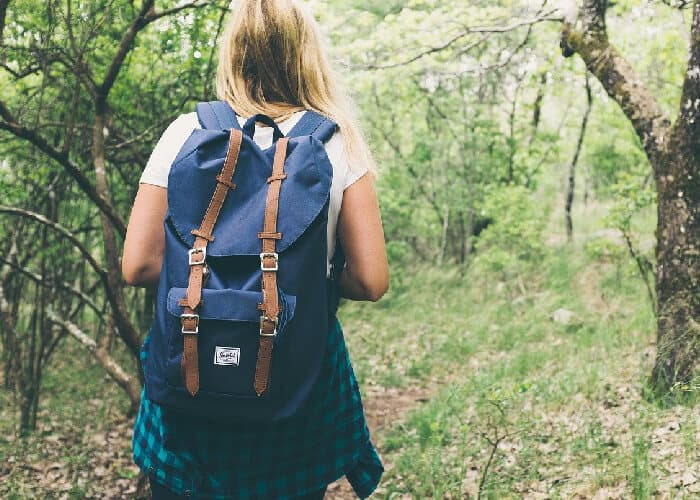 Lady with backpack walking through woods