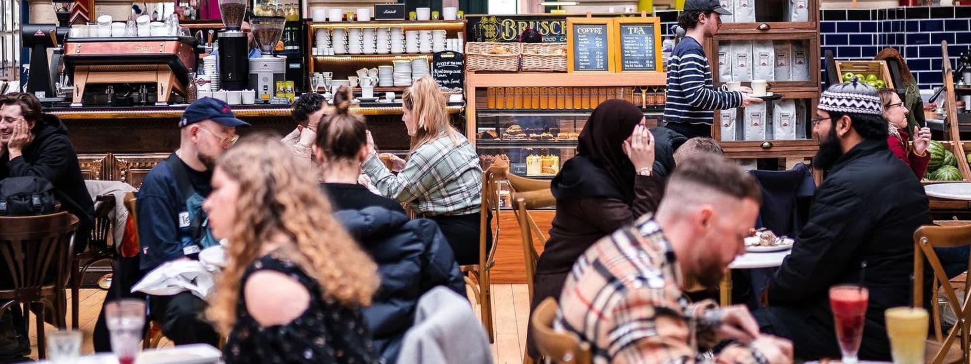 Visitors enjoying the vibrant atmosphere inside the Bruschetta cafe with a view of the coffee bar and pastry display.