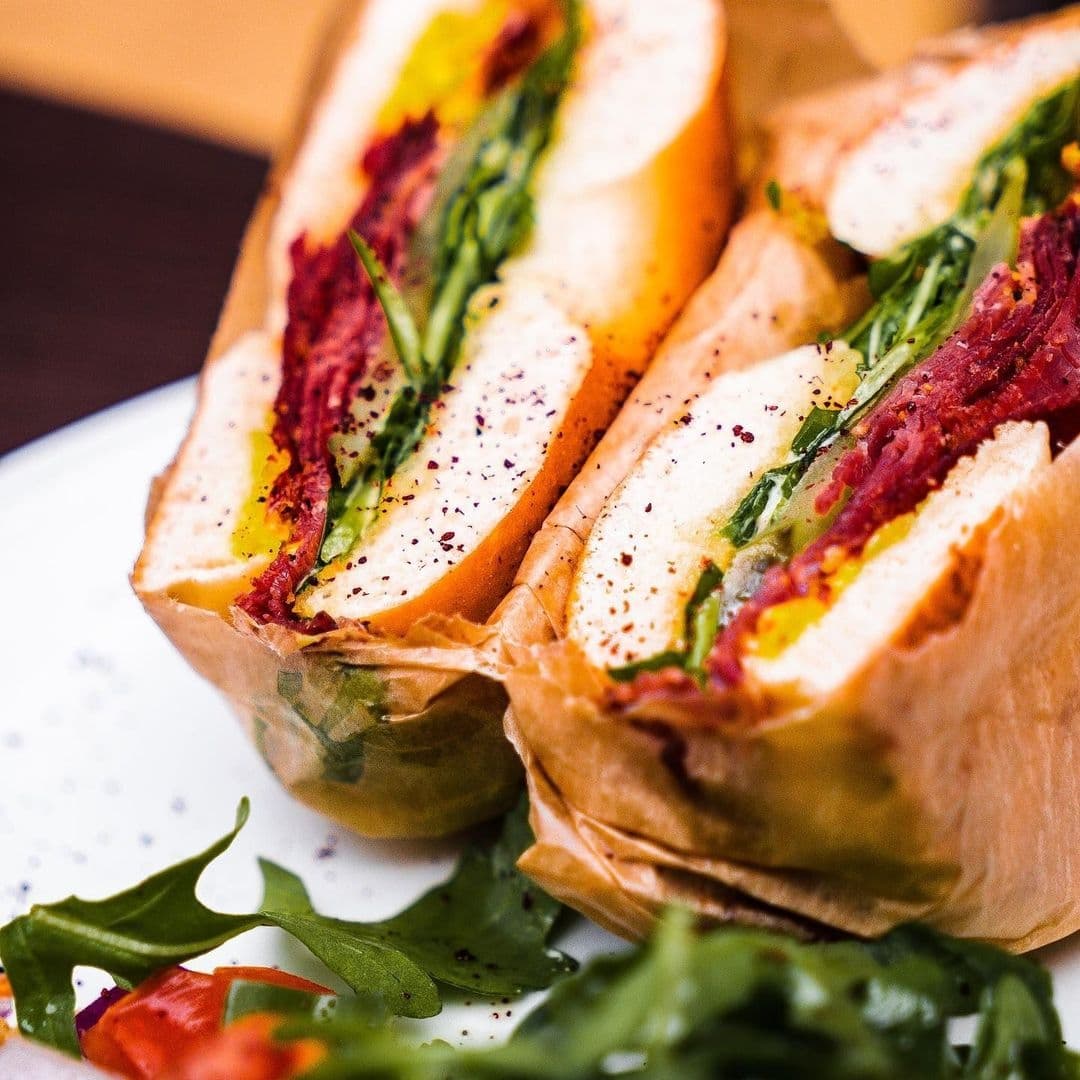 Close-up of a freshly prepared Bruschetta with vibrant toppings, garnished with arugula on a white plate.