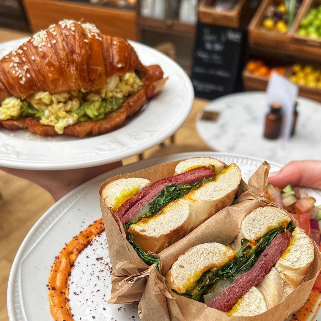 Delicious breakfast sandwiches served at Bruschetta, featuring a croissant with scrambled eggs and avocado, and a baguette with spinach and sausage.