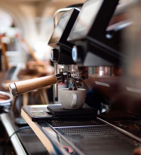 Espresso machine brewing coffee into a white cup at Bruschetta.