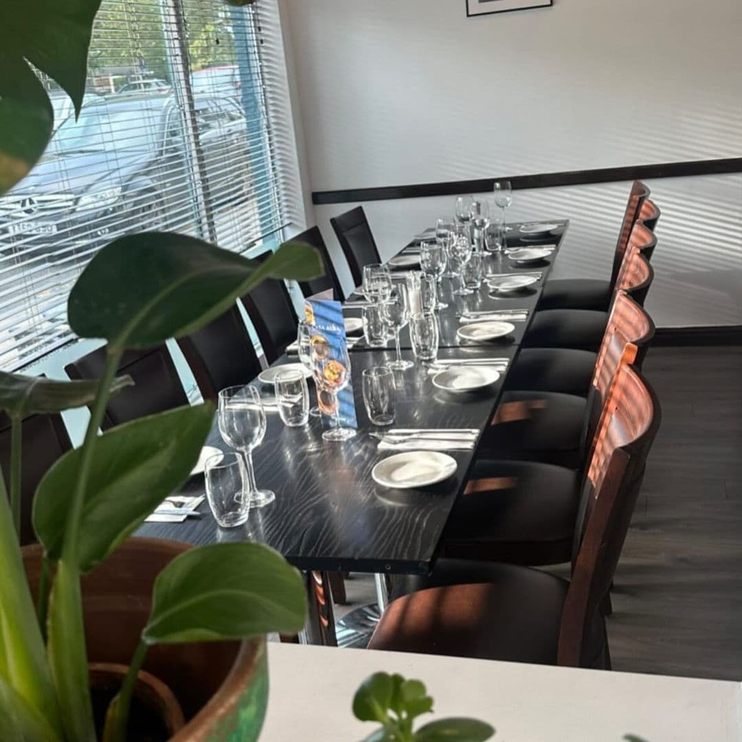 Elegant dining setup at Casa Alba with a long table, black chairs, and complete tableware under soft lighting, ready to welcome guests for a fine dining experience.