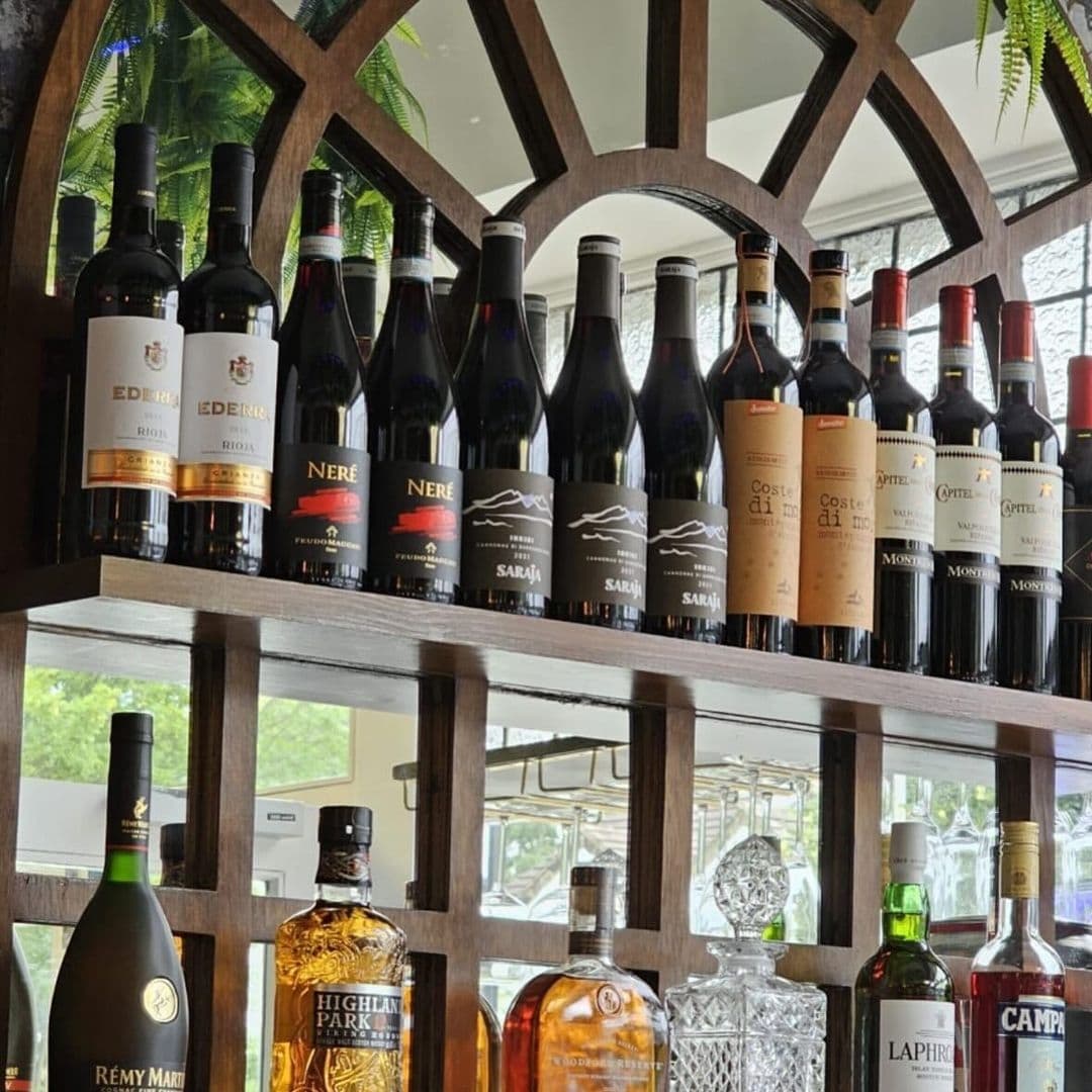 Assorted wine and liquor bottles displayed on a wooden shelf at Casa Alba.