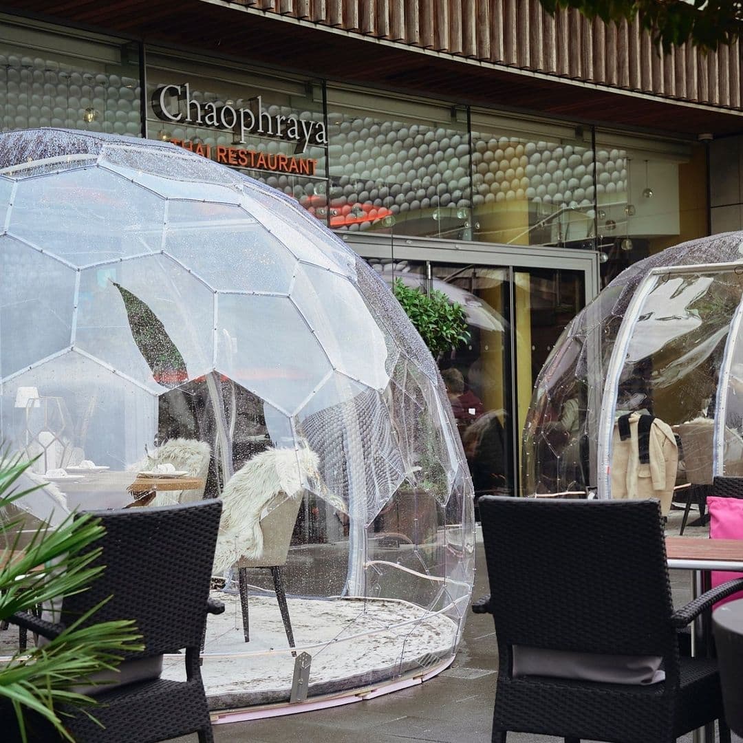 Outdoor dining area at Chaophraya Thai Restaurant with transparent dining pods and modern patio furniture.