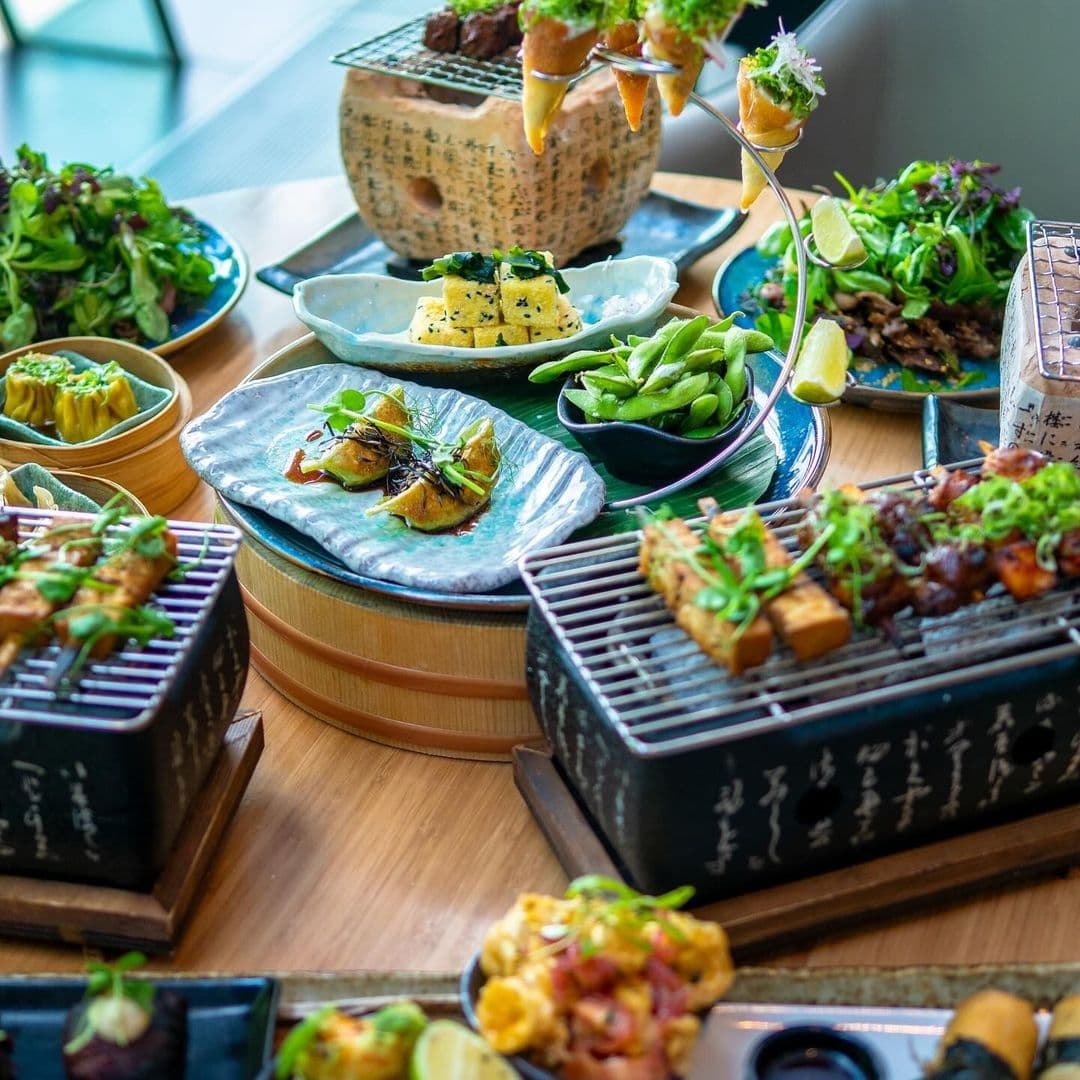 Assorted Asian-inspired dishes served at Chino Latino, featuring sushi, dumplings, edamame, and other appetizers on a wooden table.