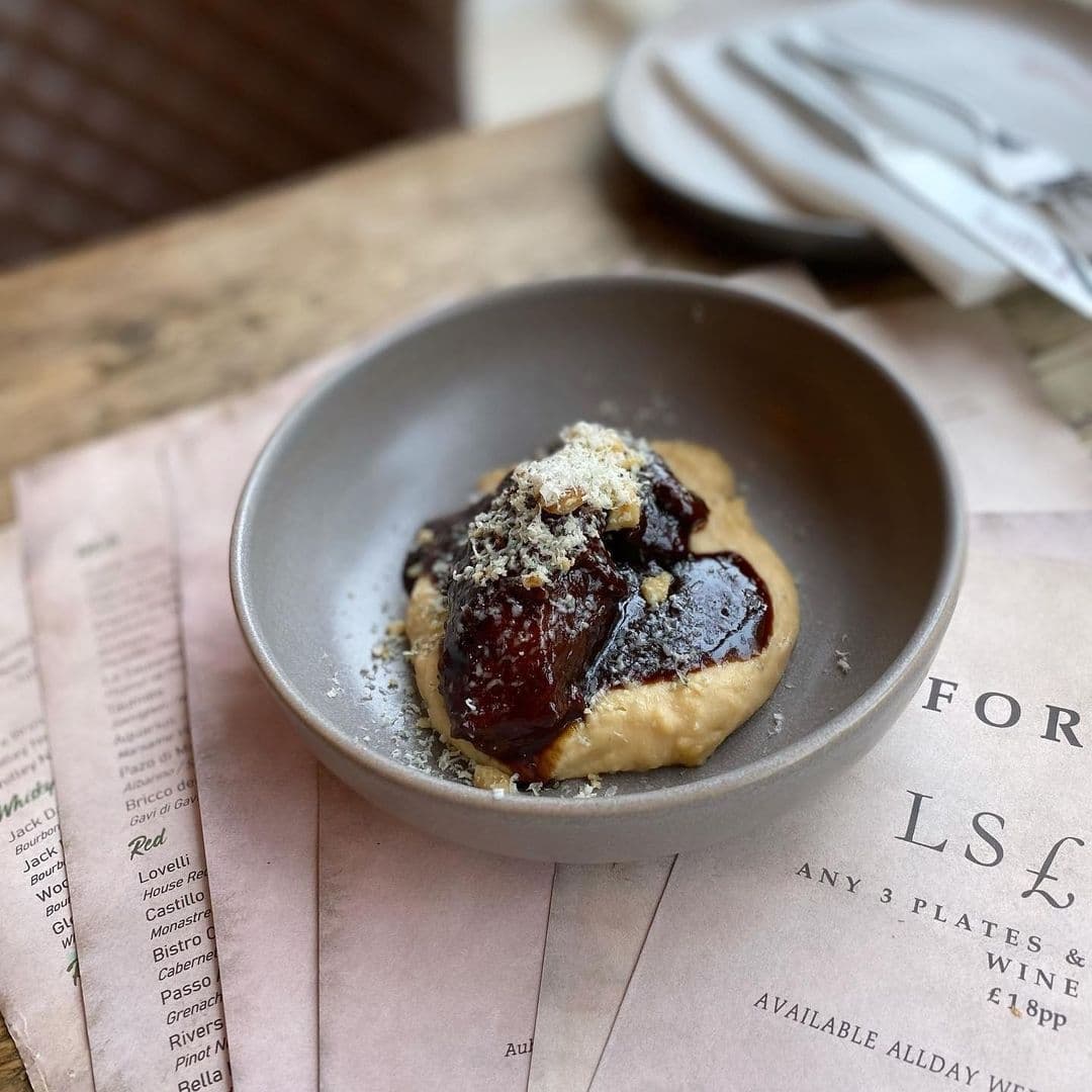 Gourmet dish on a table at Forde with a menu, showcasing local cuisine.