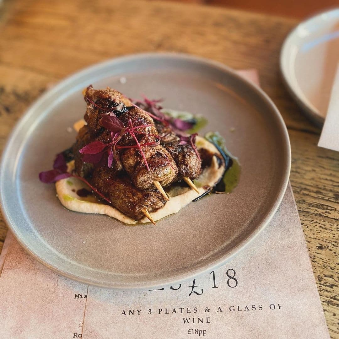 Grilled skewered meat served on flatbread with garnish on a ceramic plate, highlighting local cuisine in Forde.