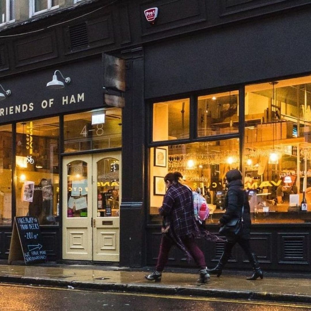Exterior view of Friends of Ham in Leeds City with pedestrians walking by on a wet street, warm lighting visible through the establishment's windows.