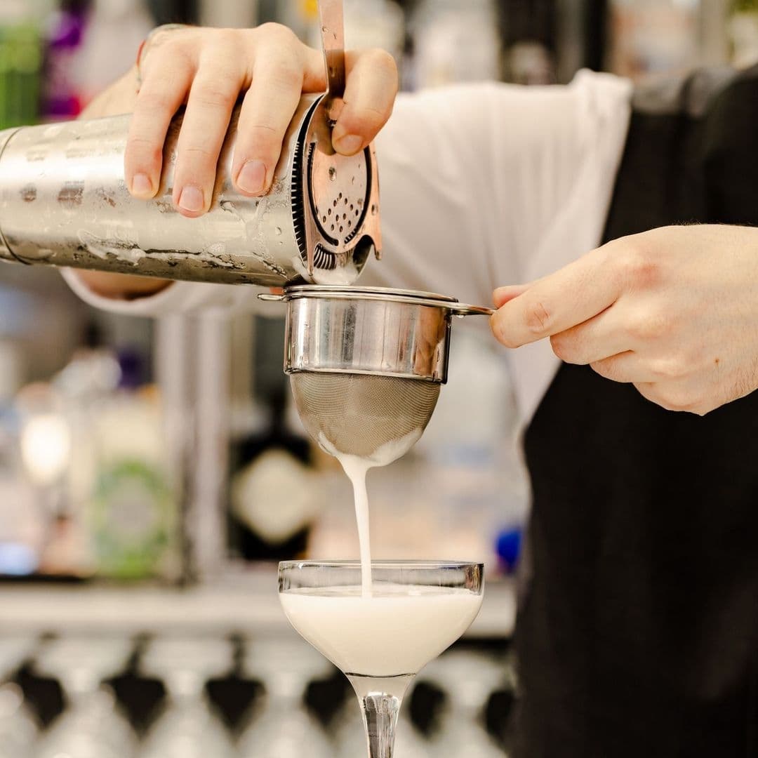 Bartender pouring a creamy cocktail through a strainer into a glass at Gaucho.