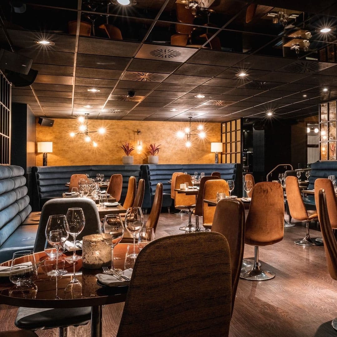 Elegant dining setup at Gaucho with modern decor, featuring plush seating, ambient lighting, and tables set with stemware.