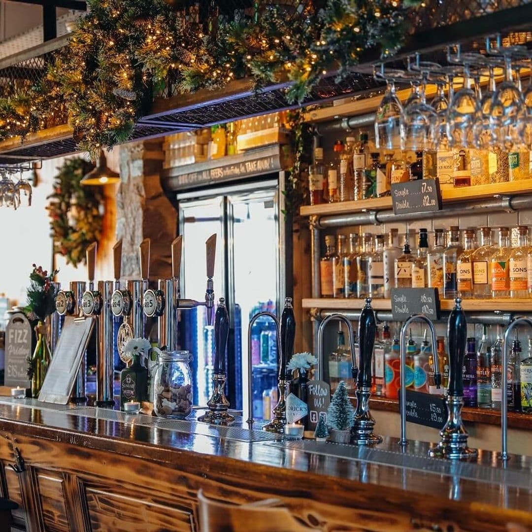 Interior of Granvilles Beer & Gin House showing a wooden bar with beer taps, assorted bottles of gin, and festive decorations.