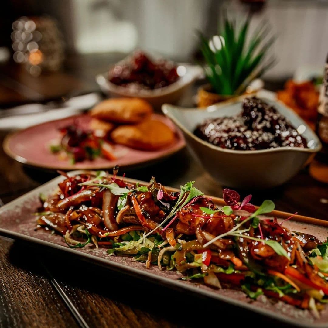 Assorted gourmet dishes on a wooden table at Jamrock, featuring a plate of vibrant stir-fried vegetables in the foreground.