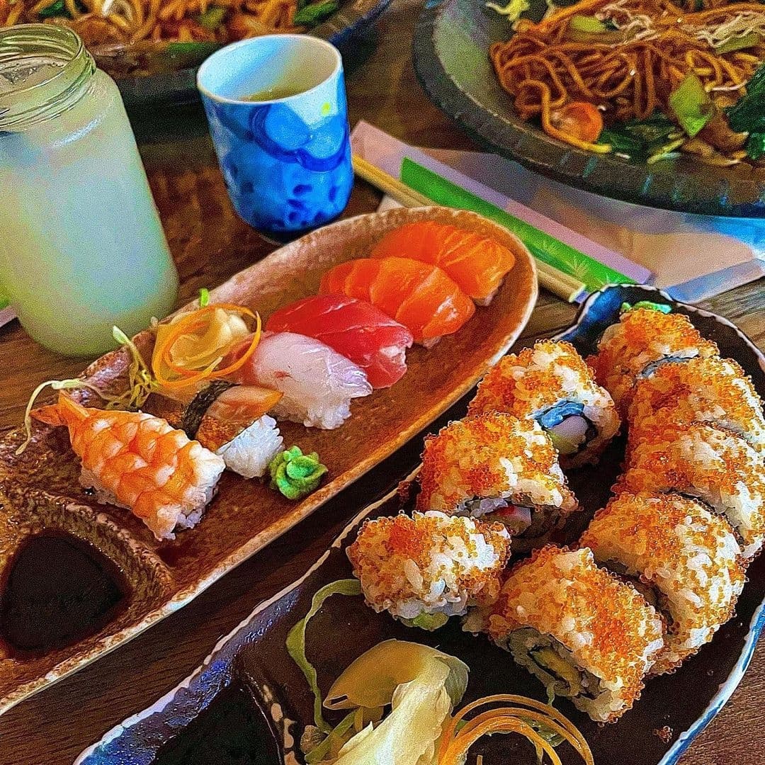 Assorted sushi and sashimi platter with a side of noodles and a drink, showcasing the culinary delights of Little Tokyo.