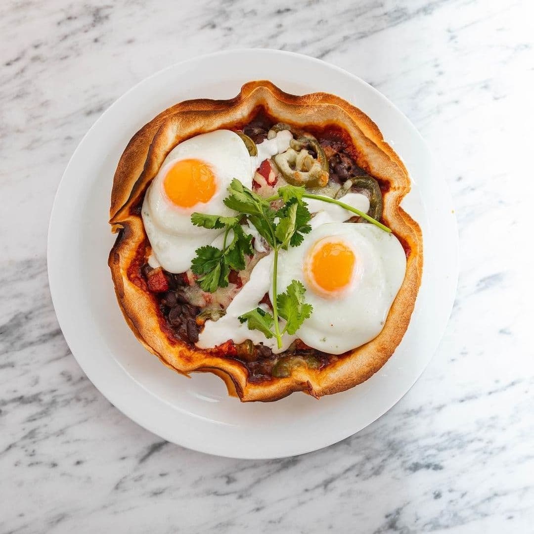 Savory breakfast dish with two sunny-side-up eggs, beans, and vegetables in a crispy tortilla bowl, served at Moose Coffee.
