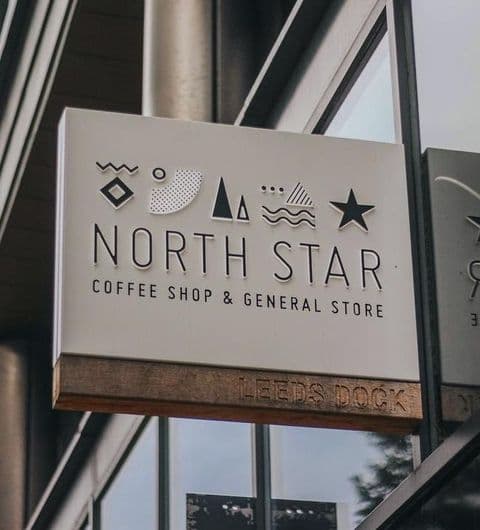 Signboard of North Star Coffee Shop & General Store at Leeds Dock with stylized icons above the text.