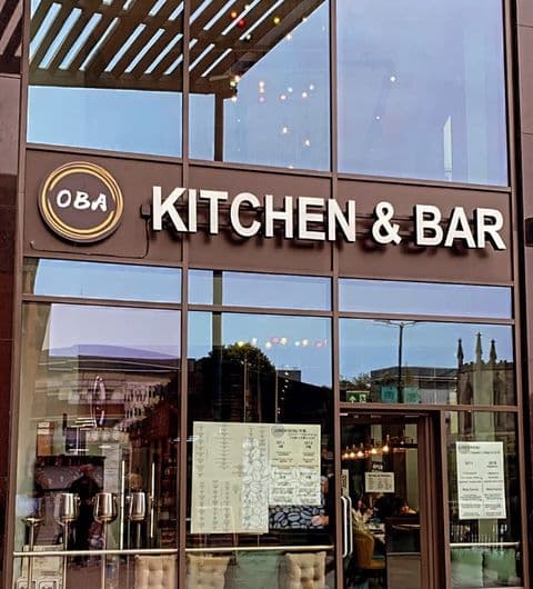 Exterior view of Oba Korean & Japanese Kitchen & Bar with signage above the entrance, reflecting the evening sky in large glass windows.