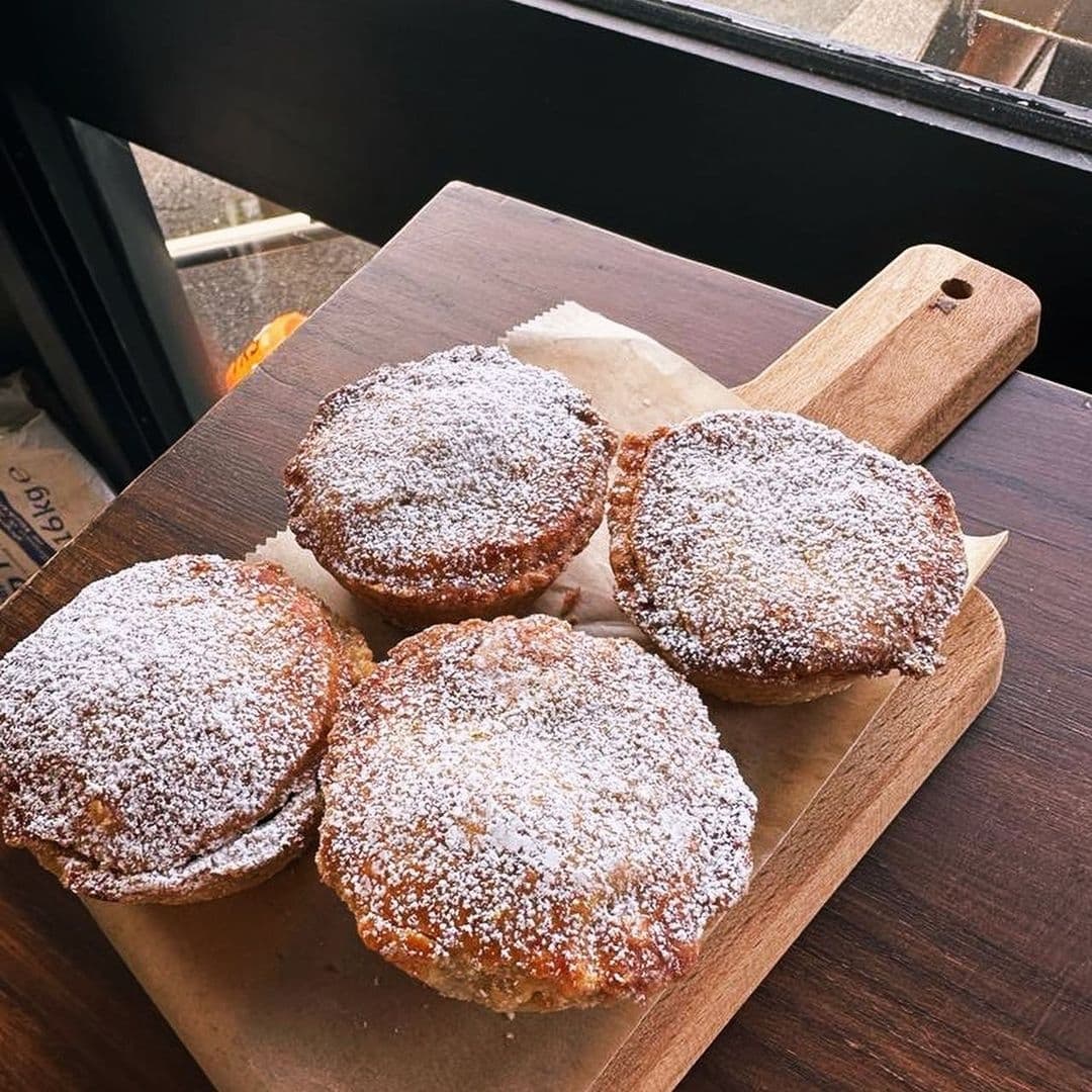 Freshly baked pastries with powdered sugar on a wooden board at Slow Rise Bakery.
