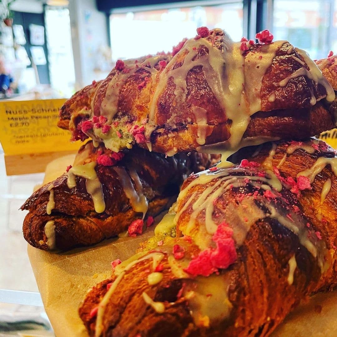 Freshly baked pastries with a drizzle of icing and sprinkled with pink toppings on display at Slow Rise Bakery.