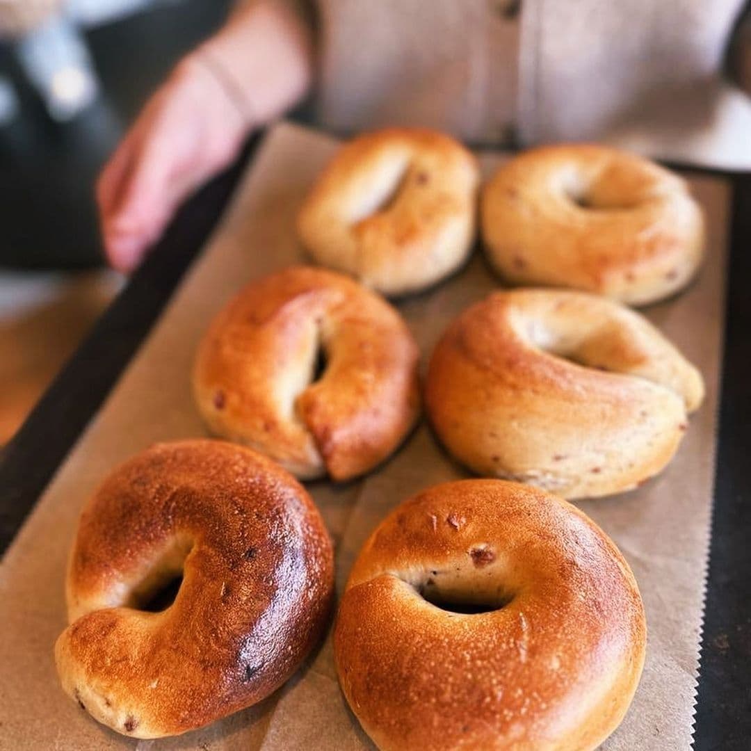 Freshly baked bagels on display at Slow Rise Bakery with a person in the background.