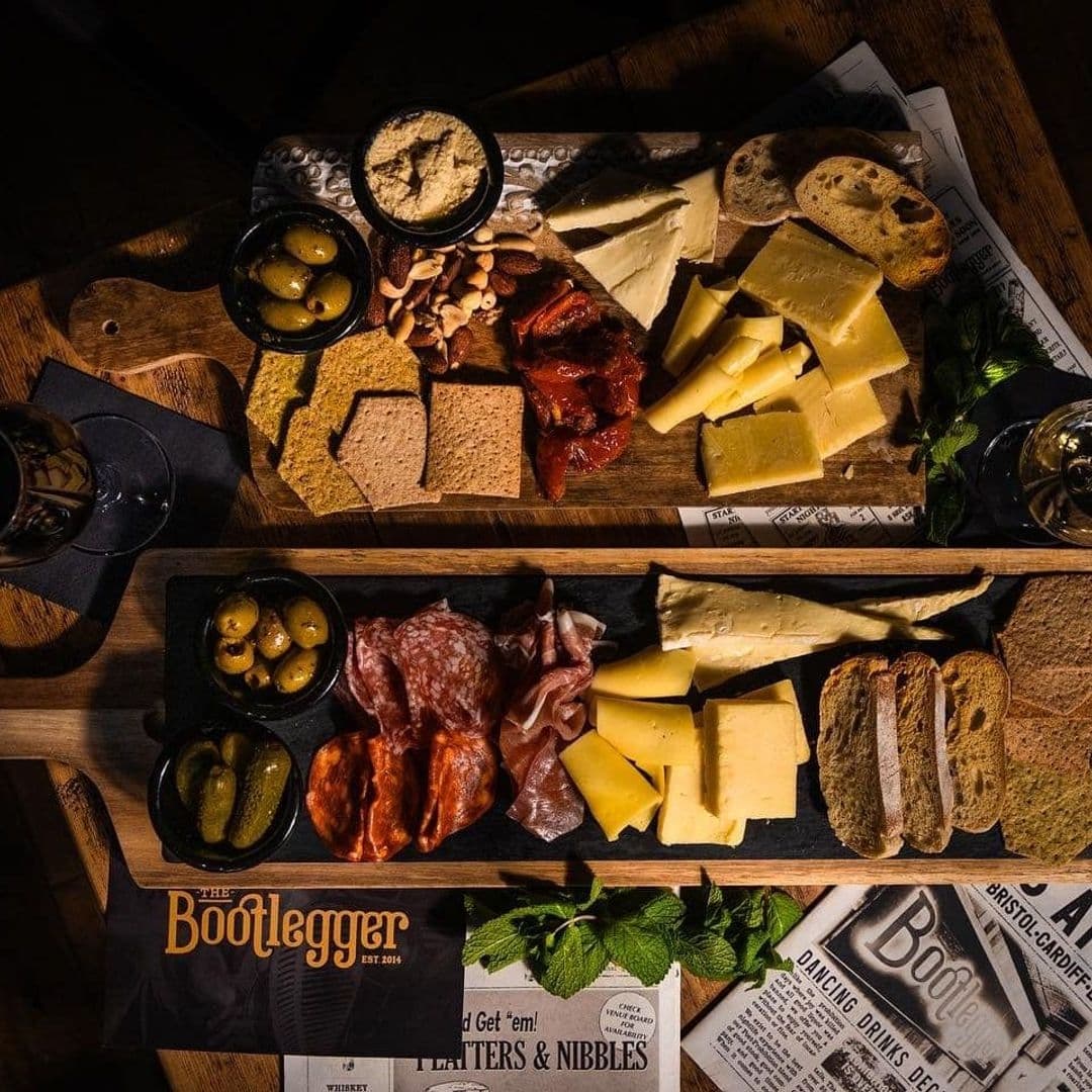 Gourmet charcuterie board with assorted cheeses, cured meats, crackers, and pickles on a wooden table at The Bootlegger.
