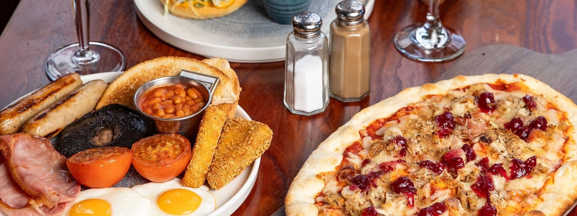 A hearty full English breakfast and a large pizza with various toppings served at The Bower's Tap.