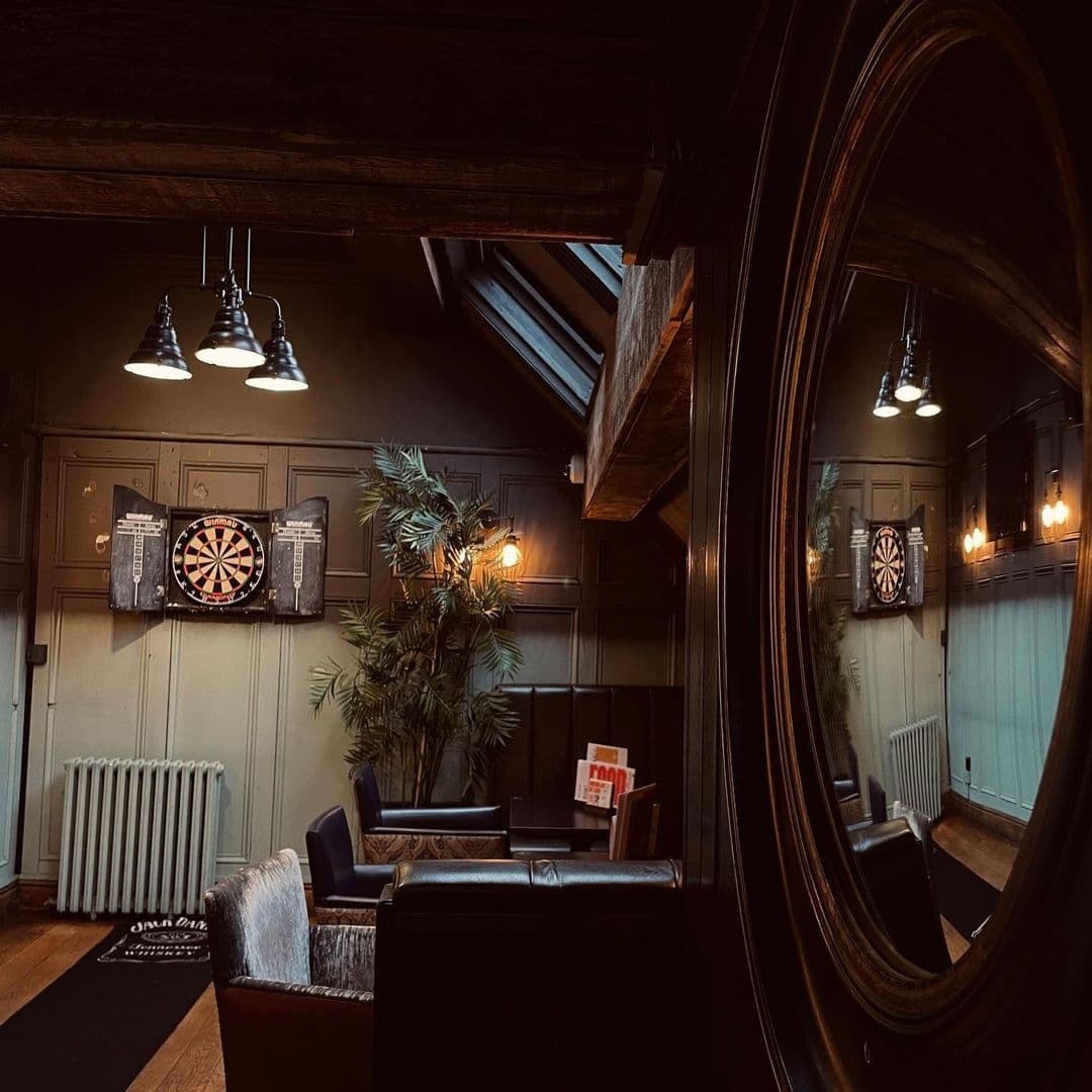 Cozy corner at The Bower's Tap featuring a dartboard, comfortable seating, and warm lighting.