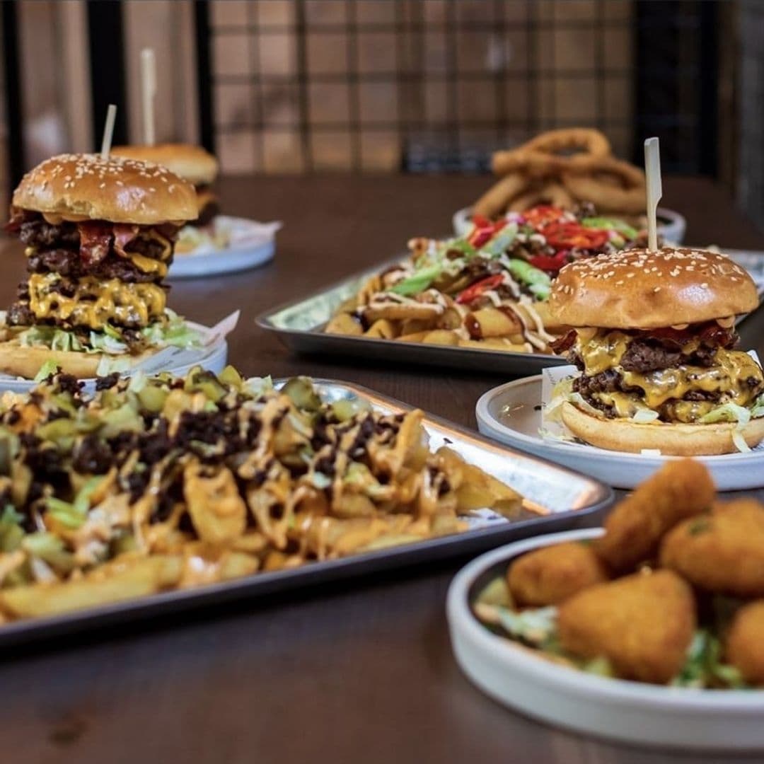Delicious pub food at The Old Kings Arms, featuring a stacked burger, loaded fries, and mozzarella sticks on wooden tables.