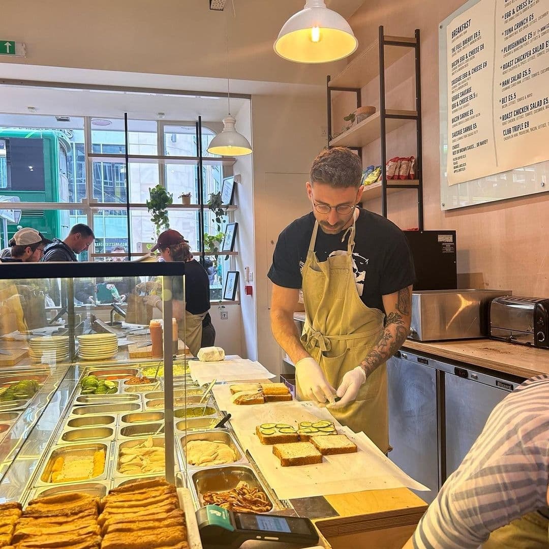 Staff preparing sandwiches at Things in Bread deli counter with fresh ingredients on display.