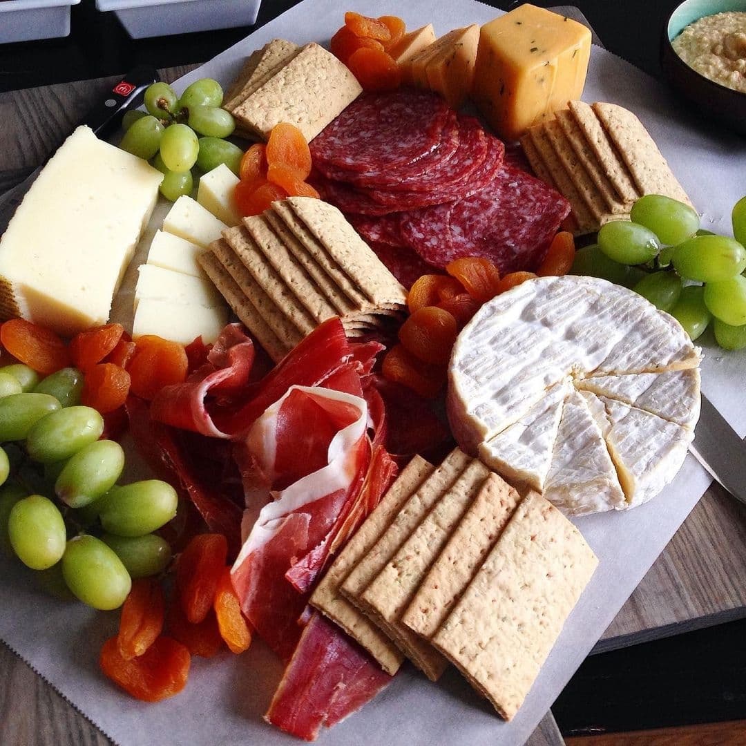 Gourmet cheese and charcuterie platter with assorted cheeses, cured meats, crackers, and fresh fruit at Victoria Social.