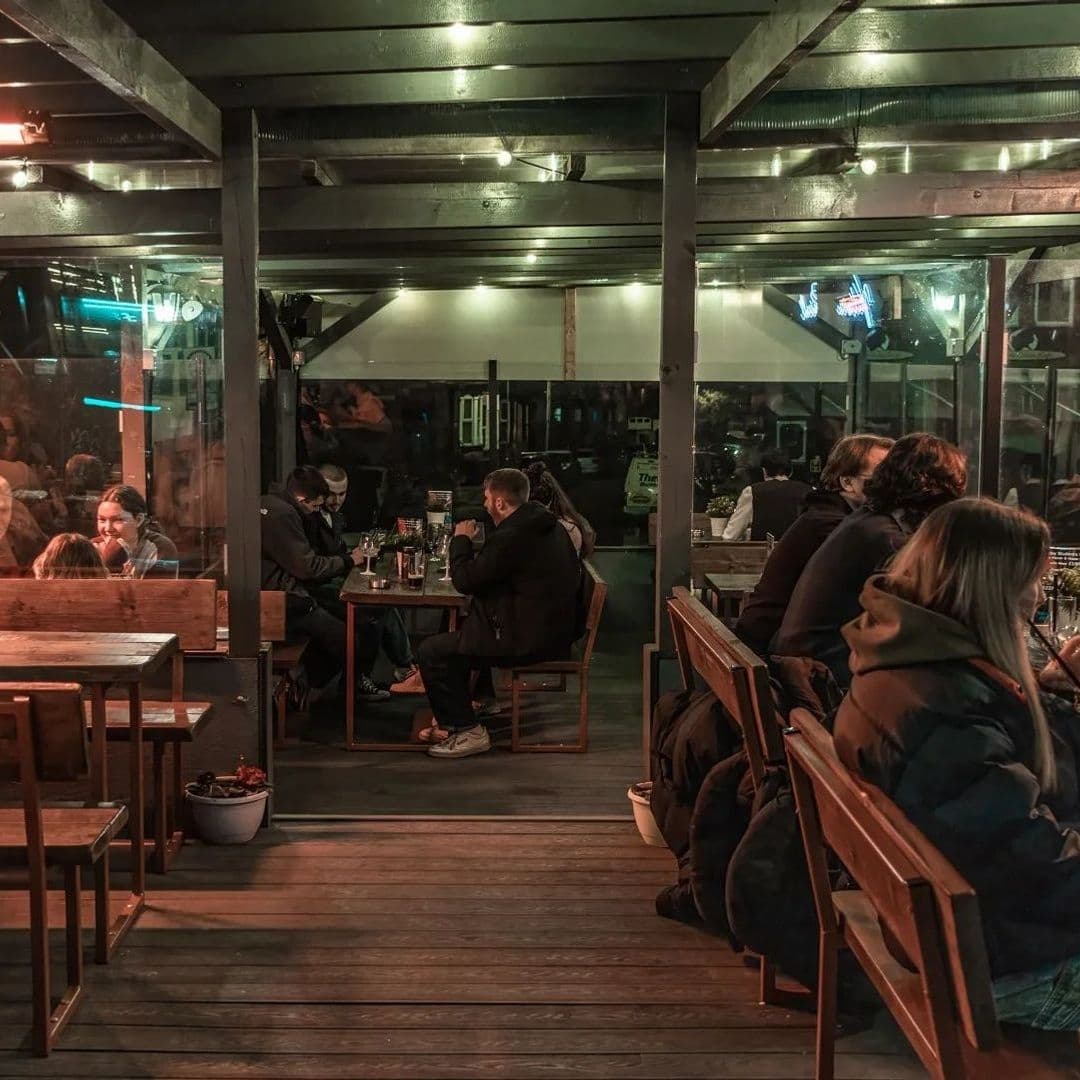 Patrons enjoying a cozy evening at Victoria Social's outdoor seating area with warm lighting and a relaxed atmosphere.