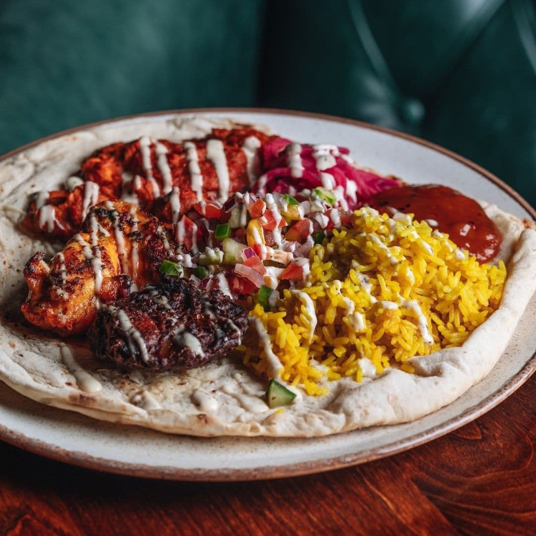 Delicious mixed grill platter served at Woolpack Inn, featuring grilled chicken, kebabs, seasoned rice, fresh salad, and flatbread.