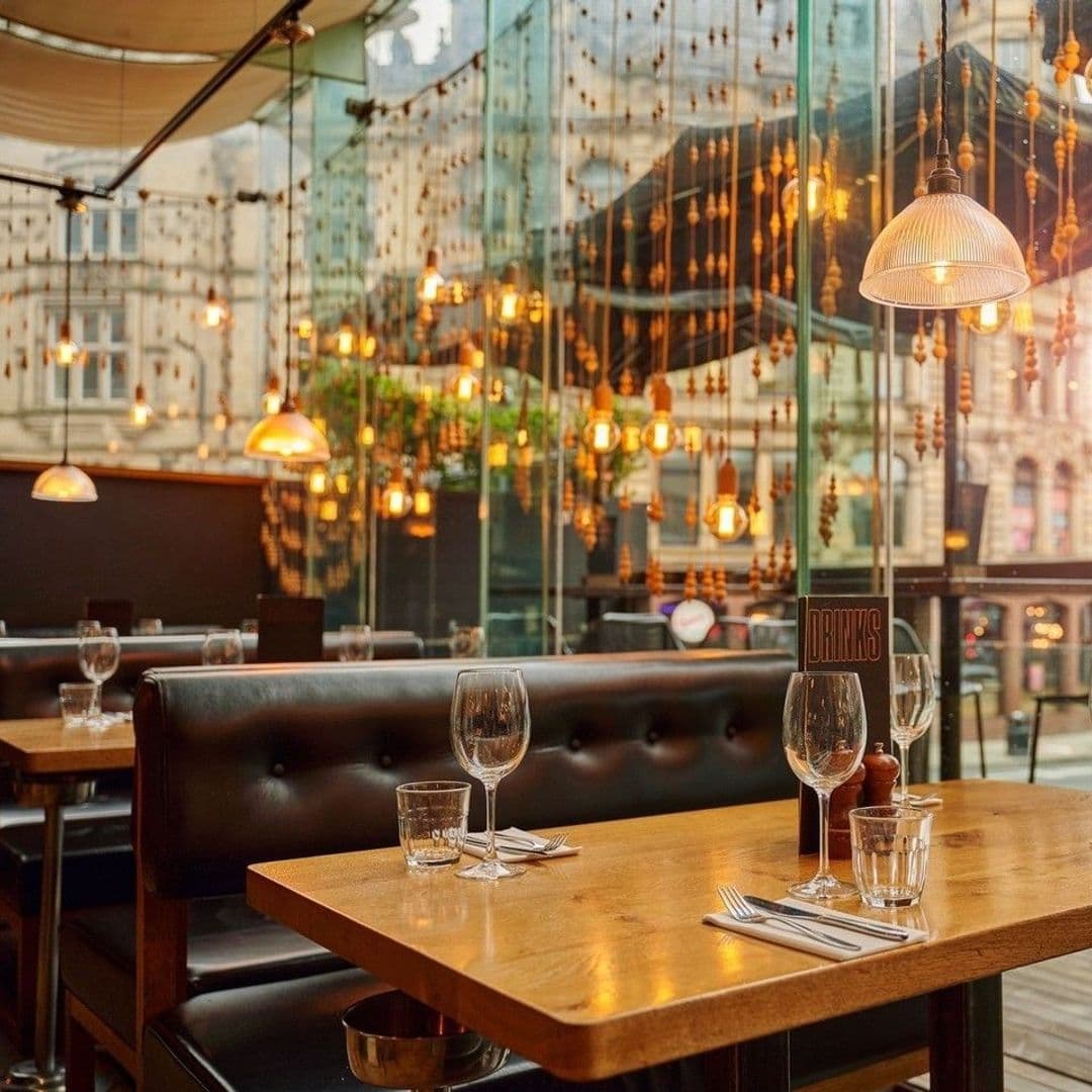 Elegant dining setup at Blackhouse with wooden tables, leather seating, and warm lighting from pendant lamps and fairy lights, offering a cozy ambiance.