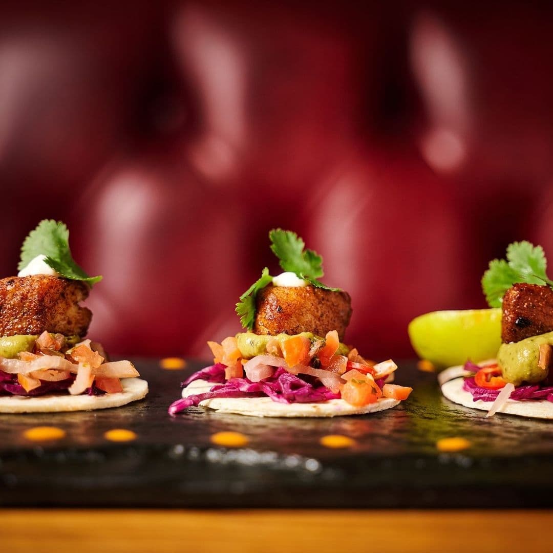 Gourmet tacos with seasoned meat, fresh salsa, and cilantro on a rustic presentation board at Blackhouse.