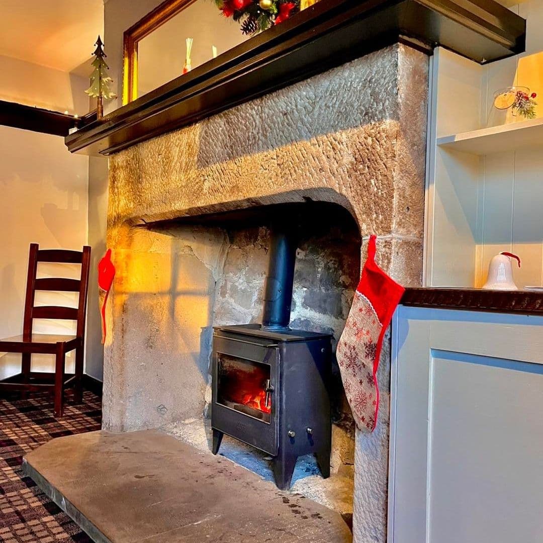 Cozy fireplace with a lit wood stove and Christmas stockings at Fox & Hounds.